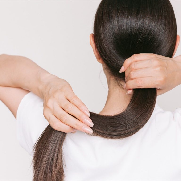 Medizinisch-ästhetische Behandlungen beim Haarausfall. Praxis für Ästhetik und Anti-Aging, Hamburg-Eppendorf. Eine Person bindet ihre langen, glatten Haare zu einem Pferdeschwanz.